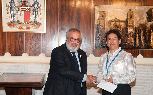 Dr Mario Vella, Governor Central Bank of Malta presenting the staff donation to Ms Esther Sant, representing Pink October